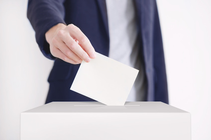 Voting. Man putting a ballot into a voting box.